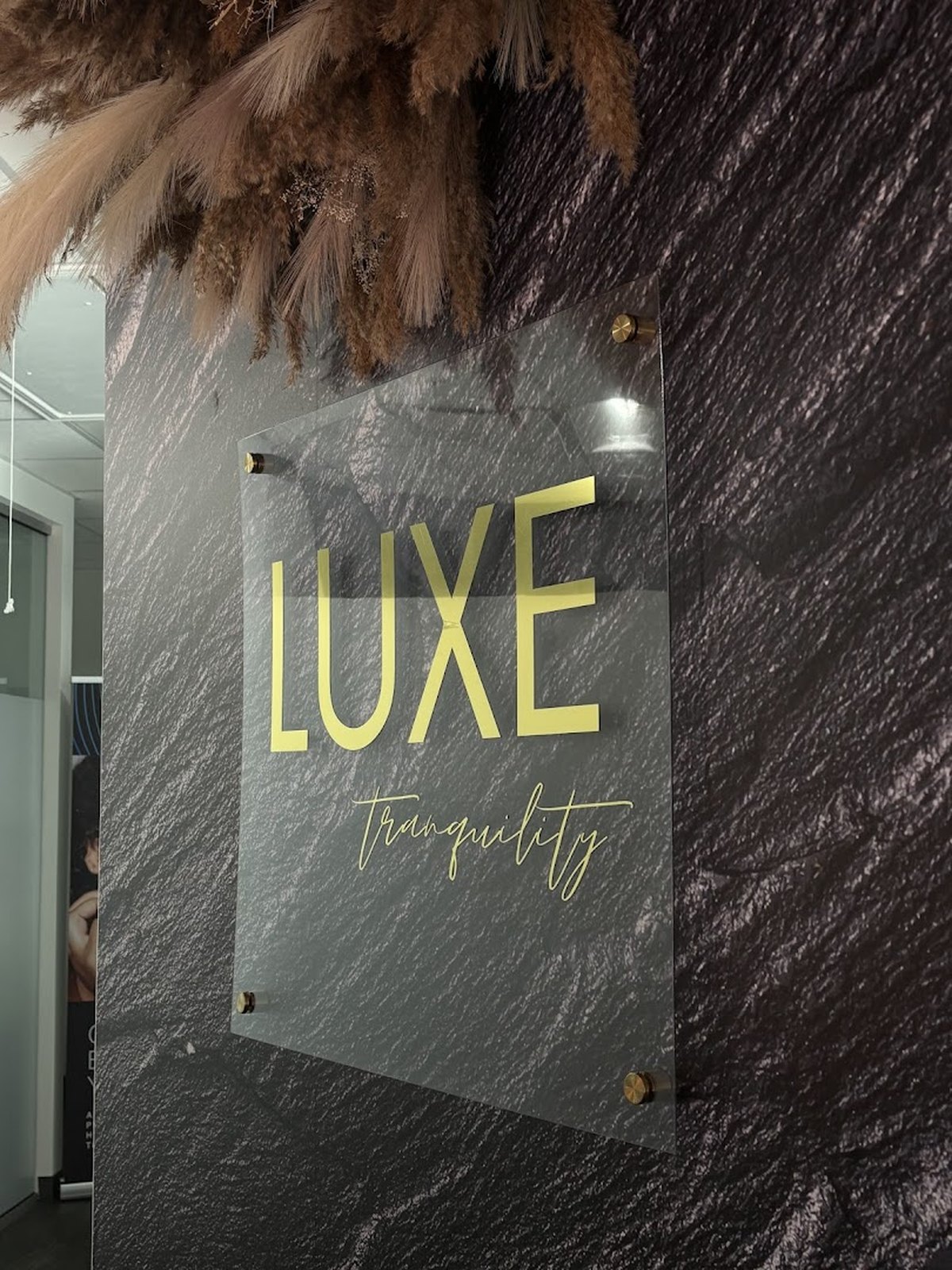 Gold Luxe Tranquility sign on a slate wall inside the Frisco med spa
